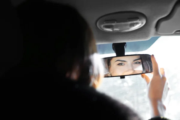 Mulher ajustando espelho retrovisor no carro — Fotografia de Stock