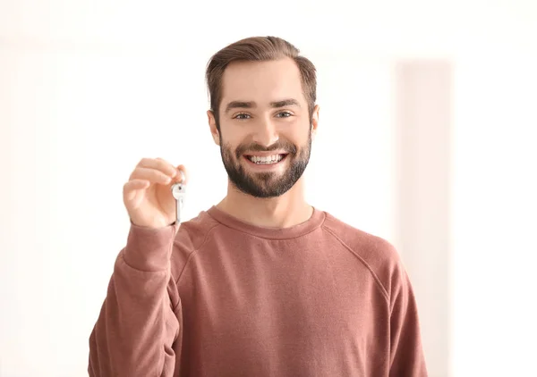 Joven sosteniendo las llaves de su nueva casa, en el interior —  Fotos de Stock