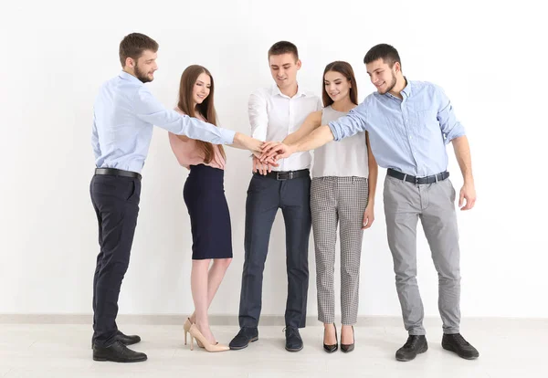 Jóvenes poniendo las manos juntas sobre fondo blanco de la pared. Concepto de unidad — Foto de Stock