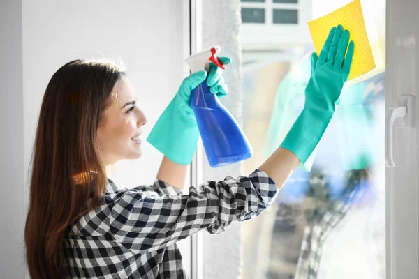 Wanita muda membersihkan jendela di dalam ruangan — Stok Foto