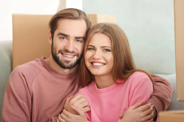 Pareja joven con cajas móviles en la habitación en el nuevo hogar —  Fotos de Stock