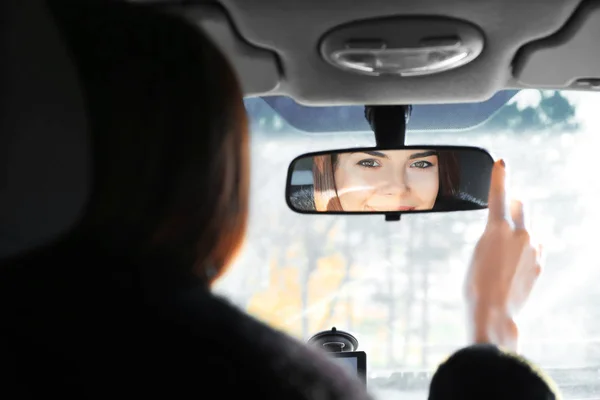 Mujer ajustando espejo retrovisor en coche — Foto de Stock