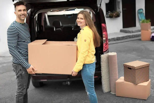 Jong paar lossen vakken van hun auto over het verplaatsen van de dag — Stockfoto