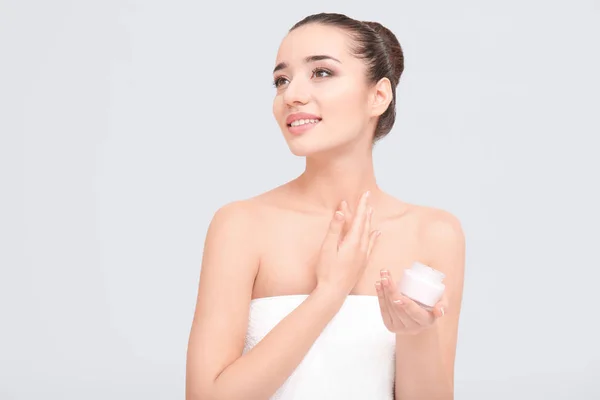 Young woman applying body cream on white background — Stock Photo, Image