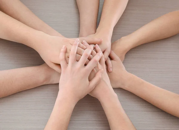 Ομάδα άνθρωποι βάζοντας τα χέρια μαζί στο ξύλινο υπόβαθρο. Έννοια της ενότητας — Φωτογραφία Αρχείου