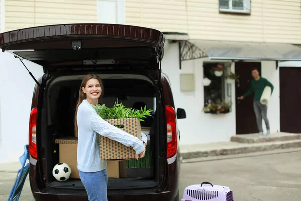 Jong paar lossen vakken van hun auto over het verplaatsen van de dag — Stockfoto