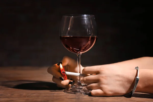 Kvinna i handbojor belysning cigarett nära glas vin. Alkoholism och nikotin — Stockfoto