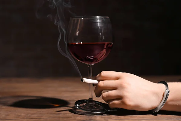 Woman in handcuffs holding cigarette near glass of wine. Alcoholism and nicotine addiction — Stock Photo, Image