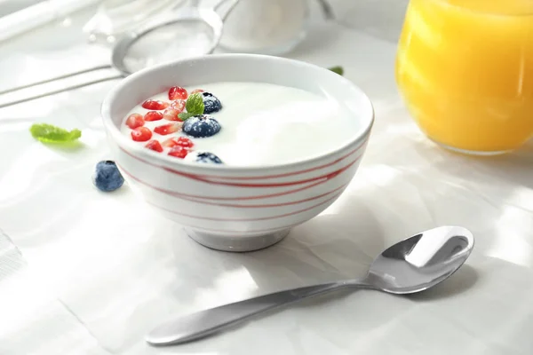 Yogur con semillas de granada y arándanos en plato sobre la mesa — Foto de Stock