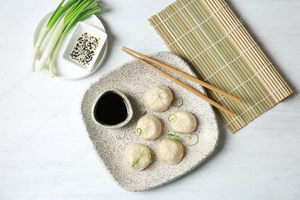 Plate with tasty baozi dumplings and soy sauce on table