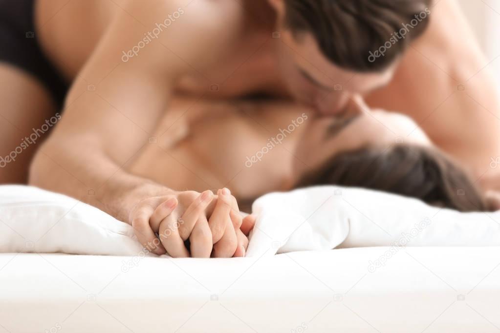 Sexy young lovers being intimate in bed, closeup