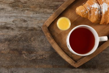 Fincan çay ve kruvasan masada, üstten görünüm ile tepsi. Lezzetli kahvaltı