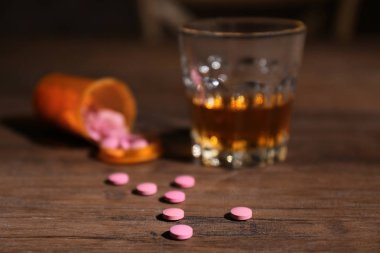 Drugs and blurred glass of alcohol on table clipart