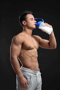 Siyah arka plan üzerine Protein içeceği içmek kas yakışıklı genç