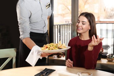 Waiter serving tasty salad at restaurant clipart