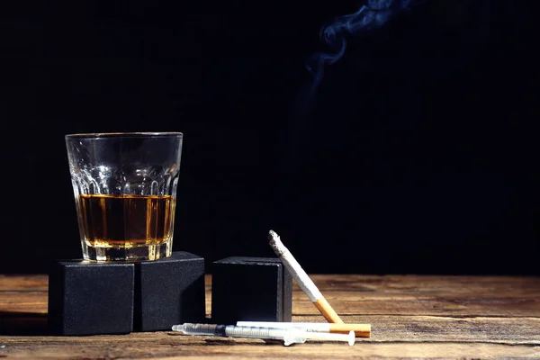 Copo de álcool, seringa e cigarros na mesa — Fotografia de Stock