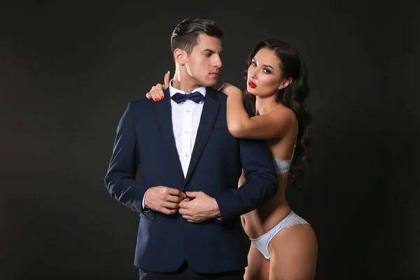 Femme sexy en sous-vêtements et homme d'affaires portant un costume sur fond sombre — Photo