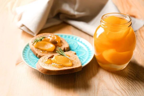 Glas und Brotscheiben mit eingelegten Aprikosen auf dem Tisch — Stockfoto