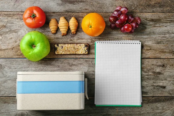 Żywności dla student, pudełko na lunch i notebook na podłoże drewniane — Zdjęcie stockowe