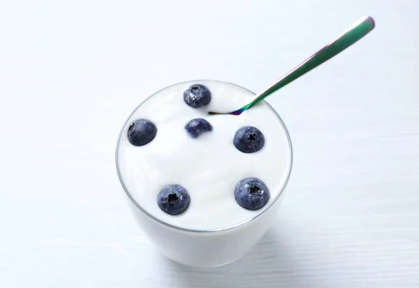 Sabroso yogur con arándanos en vidrio sobre la mesa —  Fotos de Stock