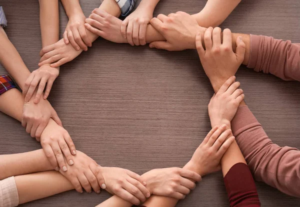 Gruppo di persone che fanno cerchio con le mani su sfondo di legno. Concetto di unità — Foto Stock