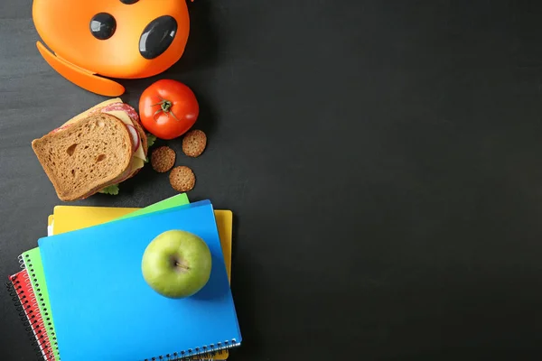 Mat för skolbarn med matlåda och anteckningsböcker på mörk bakgrund — Stockfoto