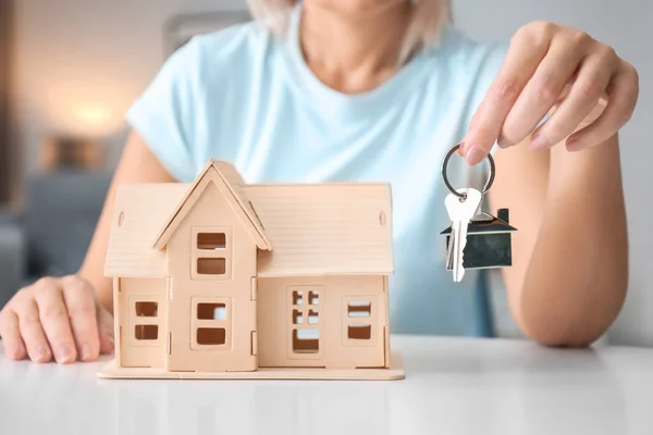 Vrouw in de buurt van huis model, close-up knop ingedrukt — Stockfoto