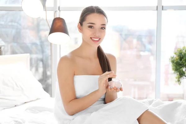 Young woman with jar of hand cream indoors — Stock Photo, Image