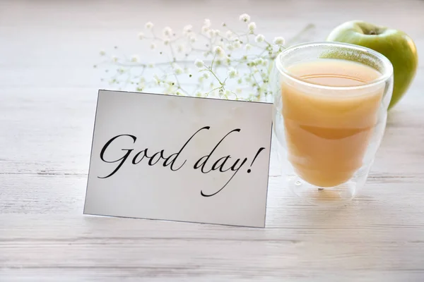 Glas juice till frukost och kort med orden ”god dag” på bord — Stockfoto