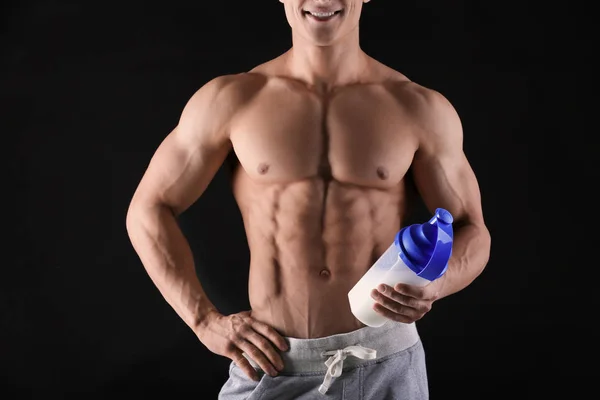 Bonito jovem musculoso com batido de proteína no fundo preto — Fotografia de Stock