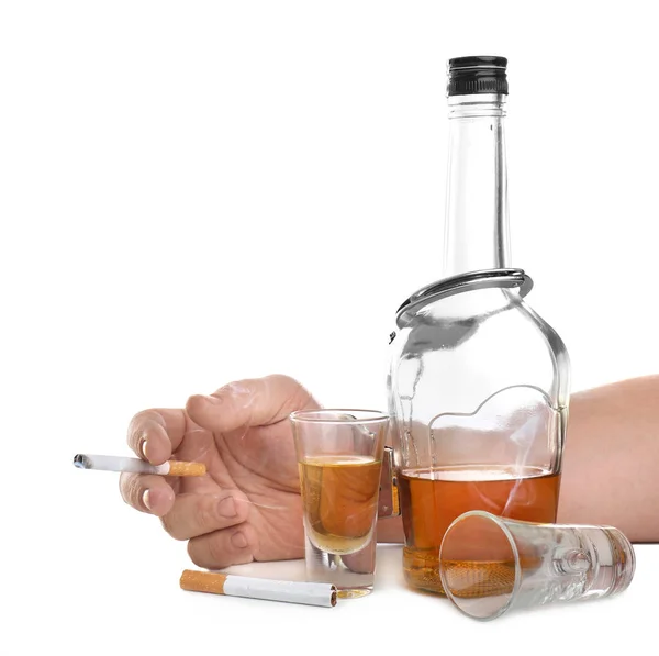 Uomo in manette in possesso di sigaretta vicino bottiglia di alcol su sfondo bianco — Foto Stock