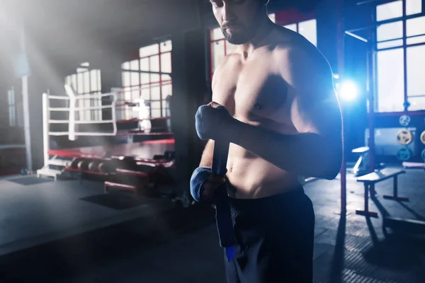 Boxer aplicando envoltórios de mão enquanto se prepara para o treinamento em ginásio — Fotografia de Stock