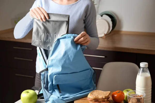 Мати кладе шкільний обідній мішок з їжею в рюкзак вдома — стокове фото