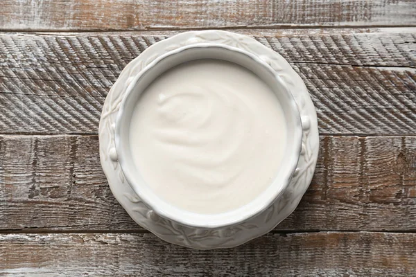 Смачний йогурт у тарілці на дерев'яному столі — стокове фото