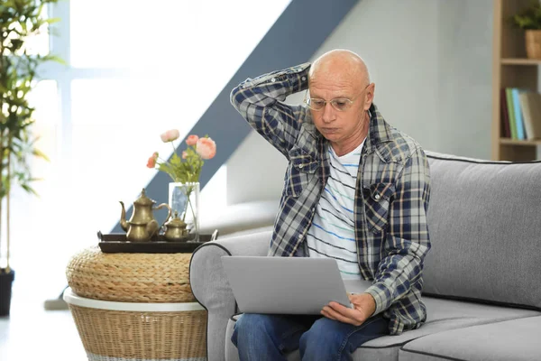 Senior man met laptop thuis — Stockfoto