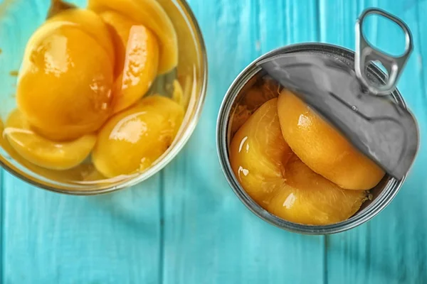 Can and bowl with pickled apricots on table — Stock Photo, Image