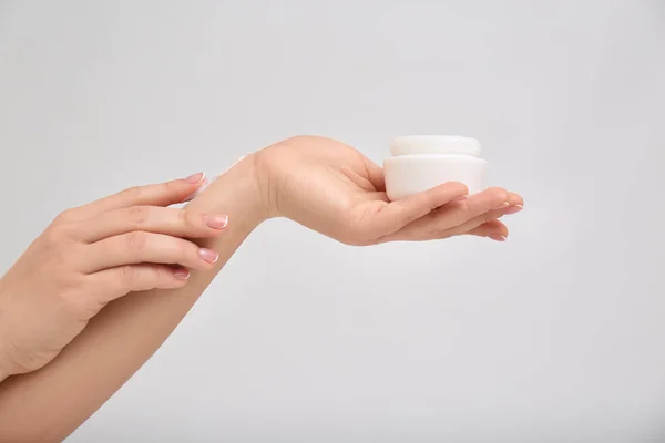 Mujer Aplicando Crema Corporal Sobre Fondo Claro — Foto de Stock