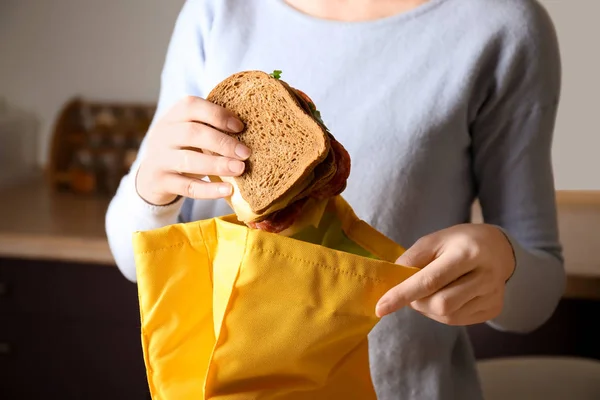 Mother packing food into school lunch bag indoors — Stock Photo, Image