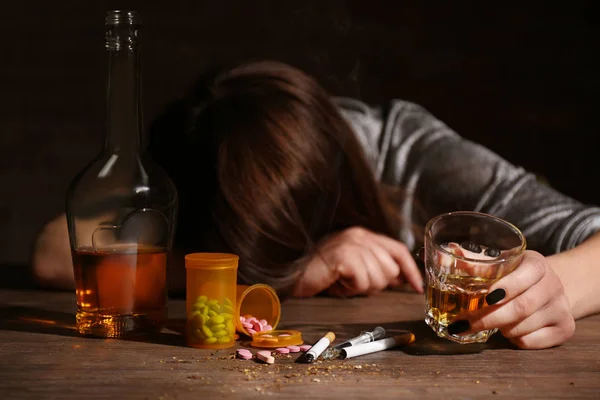 Alcohol, drugs, sigaretten en onbewuste vrouw op achtergrond Stockafbeelding