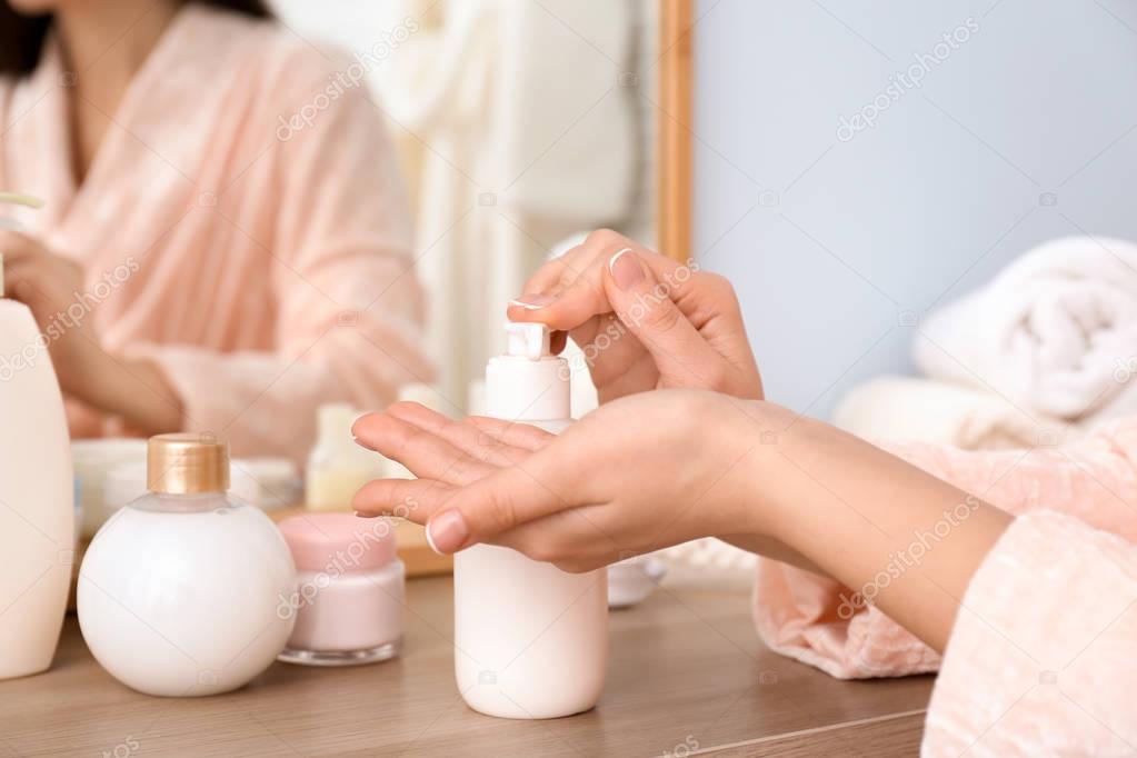 Woman with bottle of body cream indoors