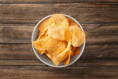 Ahşap arka plan üzerinde patates cipsi ile kase