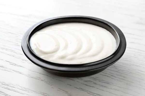 Tasty yogurt in dish on wooden table — Stock Photo, Image