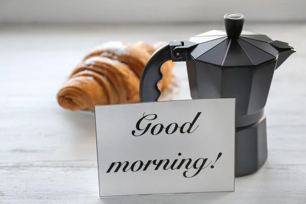 Moka pot, läckra croissanter och kort med orden ”god morgon” på bordet. Välsmakande frukost — Stockfoto