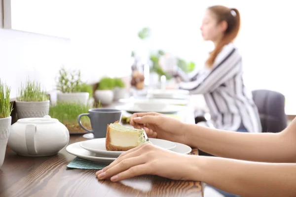 Kobieta jedzenie ciasto w pomieszczeniu. Nakrycie stołu w café wegetariańskie — Zdjęcie stockowe