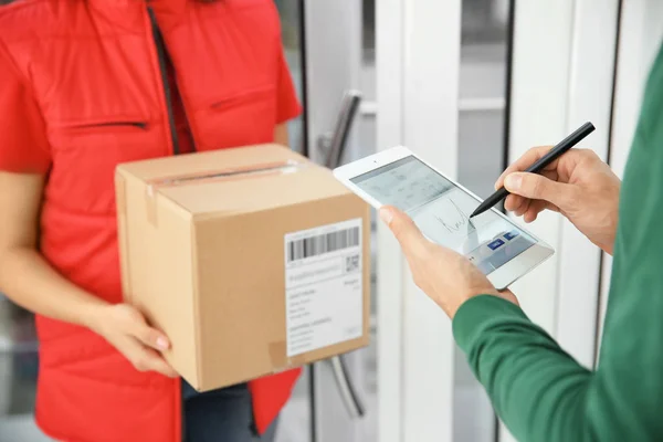 Man appending signature after receiving parcel from courier indoors — Stock Photo, Image