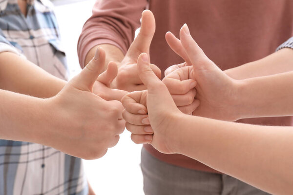 Young people standing in circle and showing thumb-up gesture as symbol of unity