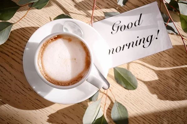 Kopp aromatiskt kaffe och kort med orden ”god morgon” på bordet. Välsmakande frukost — Stockfoto