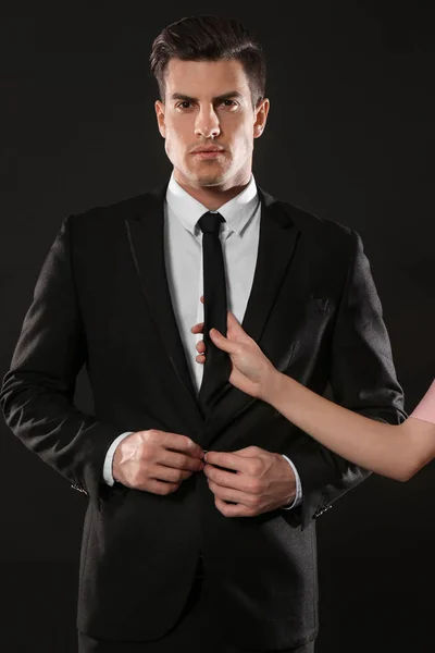 Uomo d'affari in abito e donna che tiene la cravatta su sfondo scuro — Foto Stock