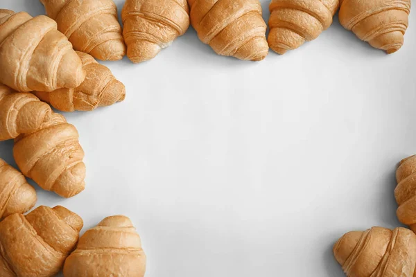 Molti gustosi croissant su sfondo chiaro — Foto Stock