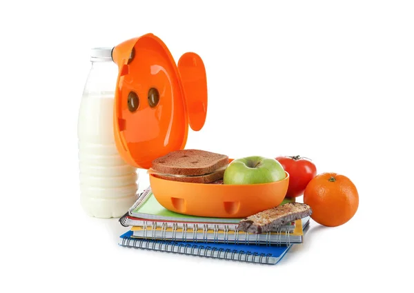 Caja de almuerzo con comida para escolares y cuadernos sobre fondo blanco — Foto de Stock